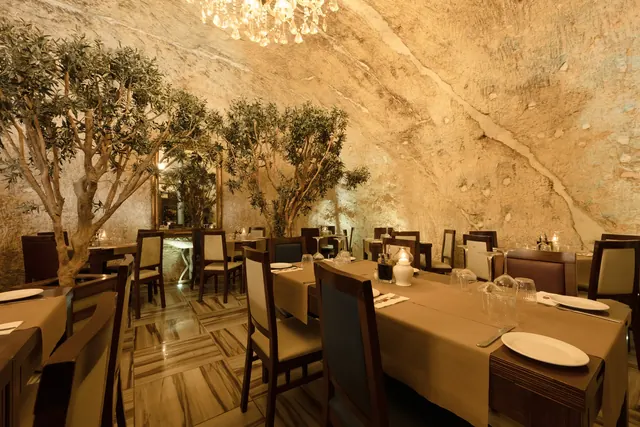 Warmly lit restaurant tables beneath a stone arch